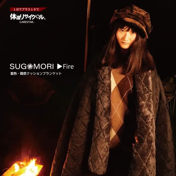 黒いSUGOMORI Fireを羽織り、焚き火のそばで過ごす女性